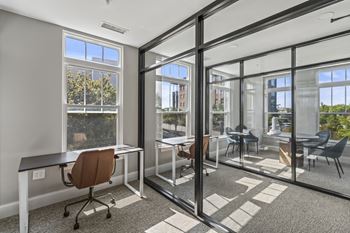 A conference room with glass doors and windows and desks